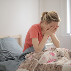 A shallow focus shot of a crying female who is lying in bed
