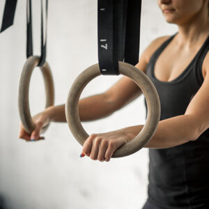 Close up of woman's hands holding gymnastic rings. Fit female working out with rings at gym.